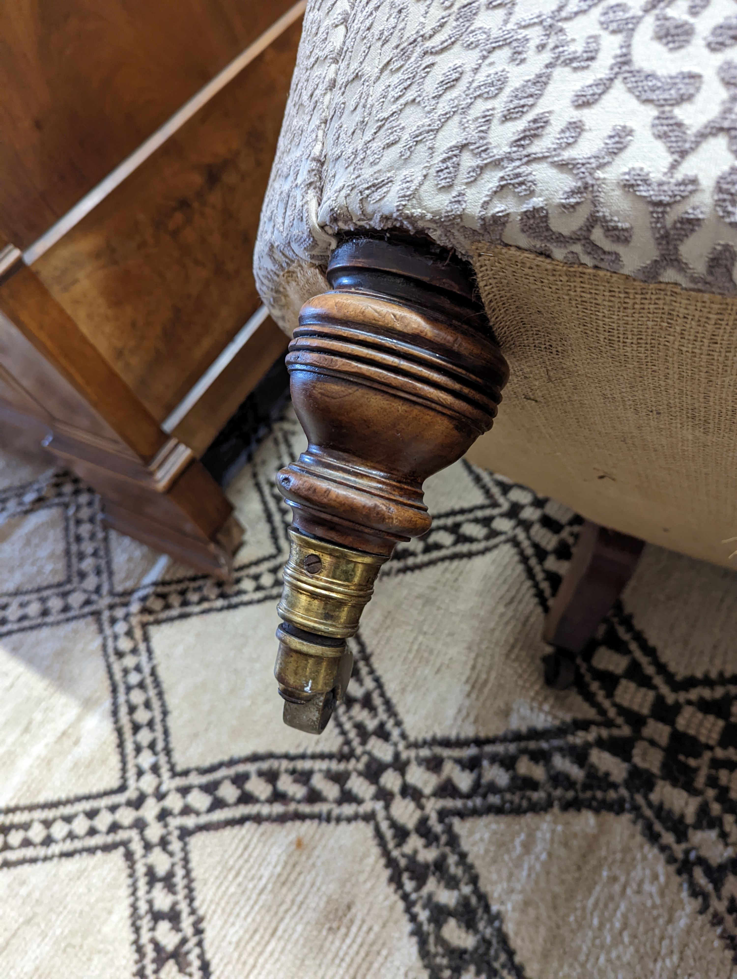 A Victorian upholstered settee with turned walnut legs, fitted brass castors, length 188cm
